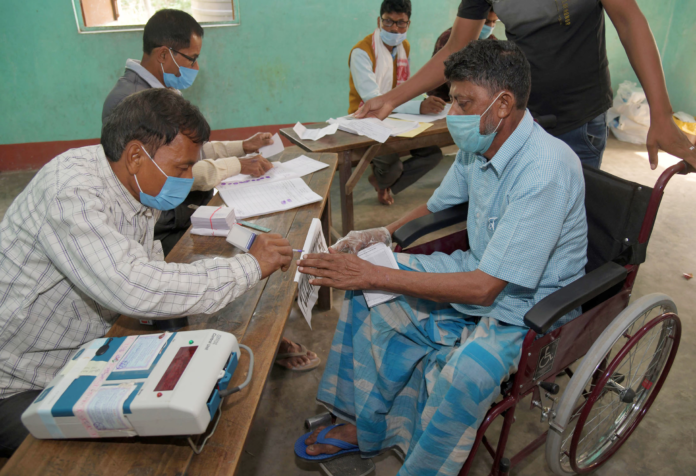 Polling official administering indelible ink to a divyang voter, at a polling booth, during the first phase of the Assam Assembly Election, at Dhekiajuli, in Sonitpur district, Assam on March 27, 2021